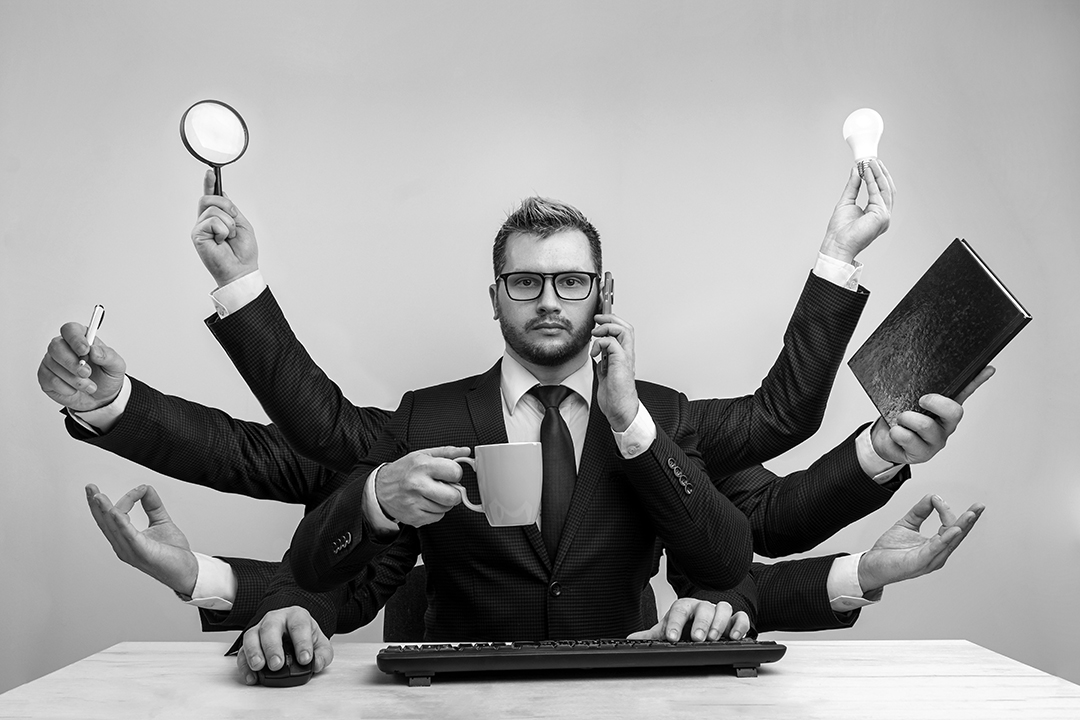 Businessman with many hands in a suit. Works simultaneously with several objects, a mug, a magnifying glass, papers, a contract, a telephone. Multitasking, efficient business worker concept